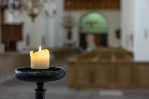Vela acesa em ambiente religioso simbolizando o velório e o sepultamento.