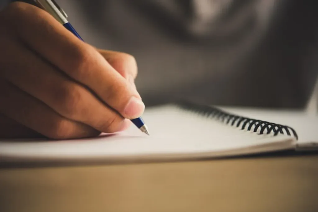 Pessoa a escrever mensagens de pêsames para amigo no caderno