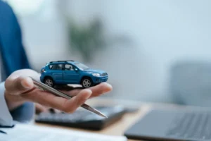 Profissional segurando miniatura de carro durante atendimento de assistência automóvel.