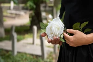Pessoa segurando uma rosa branca em cemitério, representando plano funerário e jazigo.